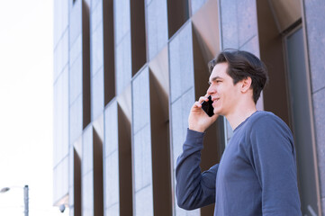 Smiling student wears a blue clothes and talks onthe phone in a commercial space