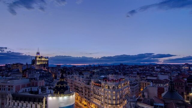 Panoramic aerial view of Gran Via day to night transition, main shopping street in Madrid Skyline Old Town Cityscape, Metropolis Building lights turn on, capital of Spain, Europe.