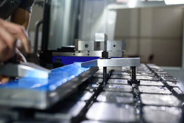 a man puts an aluminum piece on a cnc machine and prepares a processing machine..