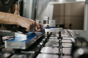 a man puts an aluminum piece on a cnc machine and prepares a processing machine..