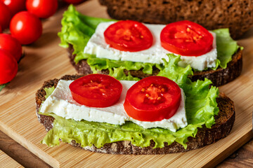 sandwich with cheese, lettuce and tomato on a wooden table