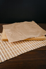 Obraz na płótnie Canvas Cutting board and a sheet of crumpled paper on a mat lies on a brown wooden table