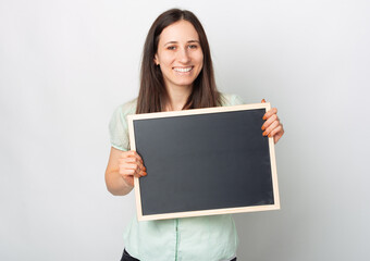 A young happy woman is holding a black board happily smiling at the camera