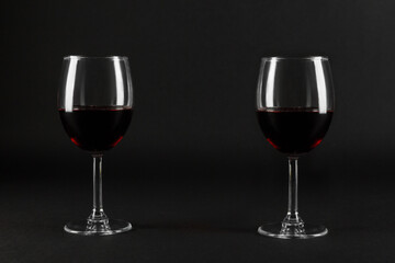 Two glass glasses of red wine on a black homogeneous background