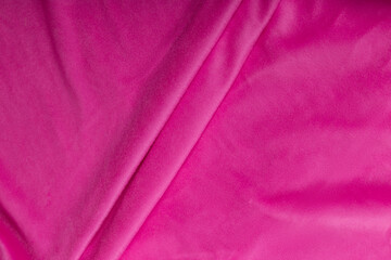 Colored rose textile satin fabric folded in folds and waves with highlights and texture