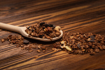 Chocolate granola cereal with nuts in a wooden spoon.