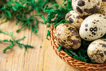 Obraz premium Aerial view of basket with quail eggs on wooden table with green grass, selective focus, horizontal, with copy space