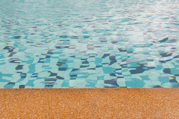 Obraz premium Close up with copy space of beautiful swimming pool with rock rim and blue clear water ripples shows vacation destination for summer holiday under sunlight, beach and water reflection.