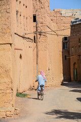 Fototapeta na wymiar Ciclista solitario per le vie di un villaggio nel deserto dell'Oman