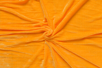 Colored orange textile satin fabric folded in folds and waves with highlights and texture