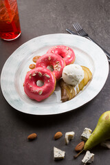 Pink donuts served with pears, ice cream and almonds