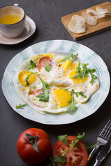 Fried eggs with tomatoes and herbs served for breakfast