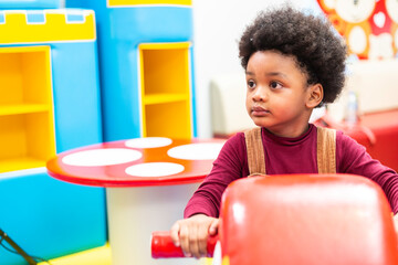 Portrait of happy African black boy playing and riding toy in a playroom