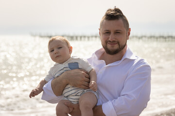 Fototapeta premium Happy father on vacation - man hugging his little baby son