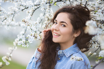 Beautiful happy girl with spring flowers. Portrait of young smiling brunette woman outdoor.