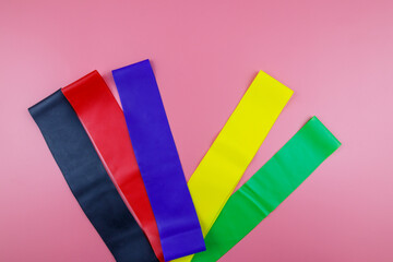 Set of elastic rubber bands for fitness on a pink background. Top view