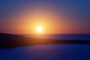 Fototapeta premium The sun sets over the sea horizon. Sunset on the sea against the backdrop of the island