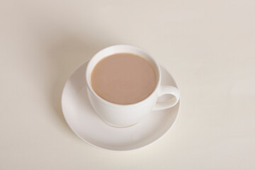White cup with coffee with milk on sandy beige trendy background. Creative postcard