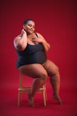 young plus size woman in swimsuit on the red background, diverse beauty