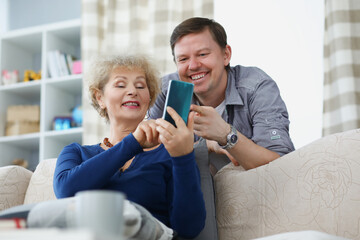 Son and mother smiling and looking at phone screen