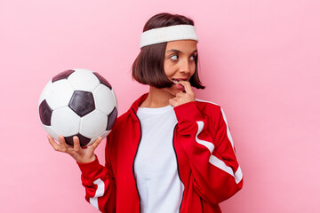 Young mixed race woman playing soccer isolated on pink background relaxed thinking about something looking at a copy space.