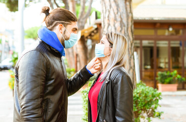 happy group of a caucasian man and a blonde woman wearing protective face mask after lockdown reopening. Young couple in a romantic sweet moment outdoor in winter. girl and a boy. new normal lifestyle