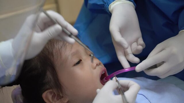 dentist doing dental procedure to young asian girl in hospital 