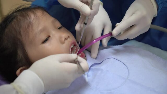 dentist doing dental procedure to young asian girl in hospital
