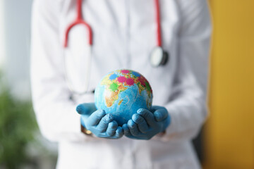 Doctor in protective gloves holding globe with viruses closeup