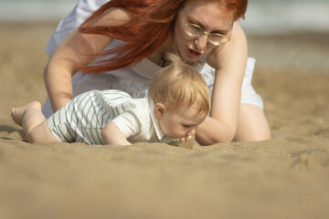 Family vacation - little boy trying to eat the sand and his mother stopping him
