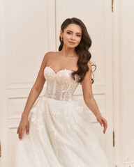 Fototapeta na wymiar Beautiful caucasian bride with long brunette wavy hair in elegant white wedding dress fashion portrait