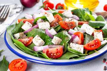 Healthy food. Greek salad with spinach, tomato, sweet pepper, red onion, feta cheese on a light background