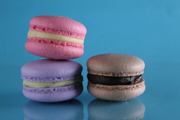 three macaroons lie triangle on a blue background with a place for text and copyspace