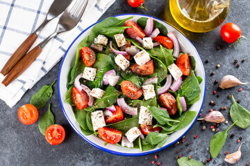 Green vegan salad from green leaves mix and vegetables. Top view on dark stone table.
