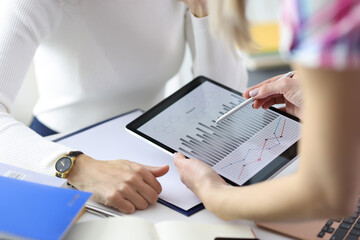 Businesswoman showing colleague graph on digital tablet closeup