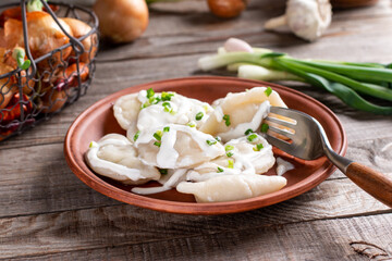 Dumplings, filled with mashed potato in plate on wooden table. Varenyky, vareniki, pierogi, pyrohy - dumplings with filling. Vegetarian dish.