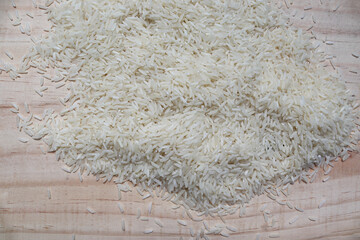 White rice pile isolated on wooden background closeup.