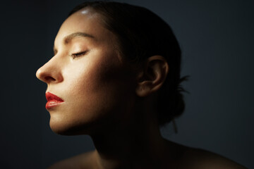 Fototapeta premium Beauty side portrait of young woman, posing over black background.