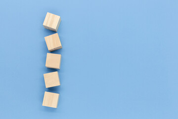 Square-shaped wooden blocks lined up high above , isolated on blue  background