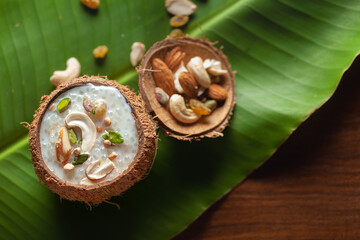 Close-up of Creamy Sabudana Kheer Garnished with dry fruits. Indian delicious dessert. Served in a coconut shell. Top View on banana leaf background.