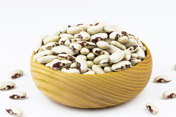 Beans of white-brown color in a wooden bowl isolated on a white background.