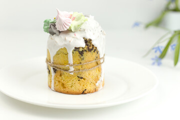 Orthodox Easter cake on white plate with blue spring flower side view on table