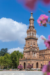 Spanish Square, in the center of Seville. Very touristic travel destination empty due to coronavirus measures. View of the south tower. Coloured flowers, blue  sky with few clouds. 