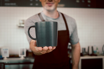 Close up of barista hands holding a cup of hot coffee in the cafe shop,  waiter staff serving coffee to customer in coffee shop counter bar.