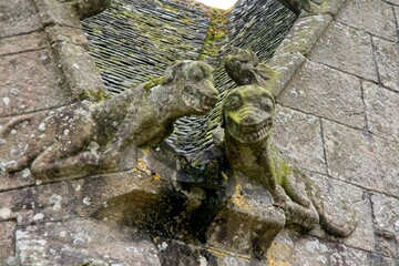 Two gargoyles worn by the elements at Plougonven Parish close in Bretagne France
