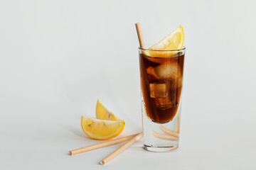 Glass of cola with ice, lemon and straw on a white background