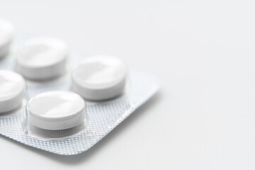 White pills in blister on white background