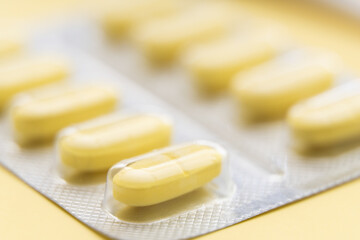Yellow pills in blister on yellow background