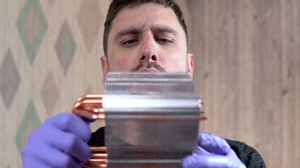Obraz premium The man blows the dust off the heatsink of the pc's central processor with his mouth. Home pc maintenance and upgrade