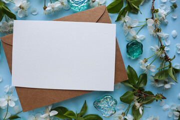 spring greeting card mockup. blooming cherry branches, envelope and white blank for text 
